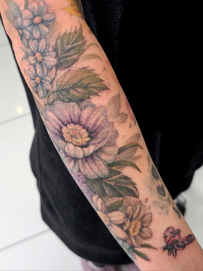 Colorful floral tattoo sleeve with ladybug details